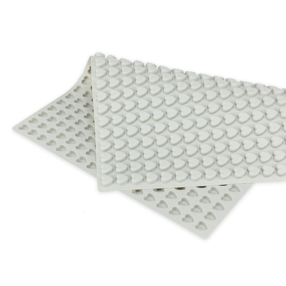 Detailaufnahme einer grauen Silikon-Backmatte mit vielen kleinen herzförmigen Vertiefungen. Die Matte ist teilweise aufgerollt und liegt auf einer weißen Fläche. Sie eignet sich zum Backen oder Einfrieren von Mini-Leckerlis für Haustiere. 1.2cm Herzform Grau