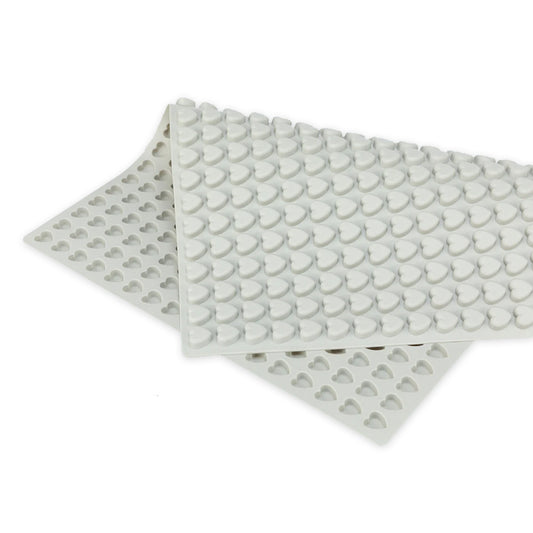 Detailaufnahme einer grauen Silikon-Backmatte mit vielen kleinen herzförmigen Vertiefungen. Die Matte ist teilweise aufgerollt und liegt auf einer weißen Fläche. Sie eignet sich zum Backen oder Einfrieren von Mini-Leckerlis für Haustiere. 1.2cm Herzform Grau