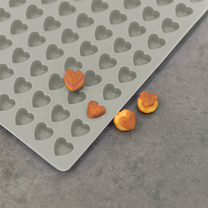 Nahaufnahme einer Trixie Backmatte 1.2cm Herzform Grau. Auf und neben der Backmatte sind herzförmige Kekse zu sehen.