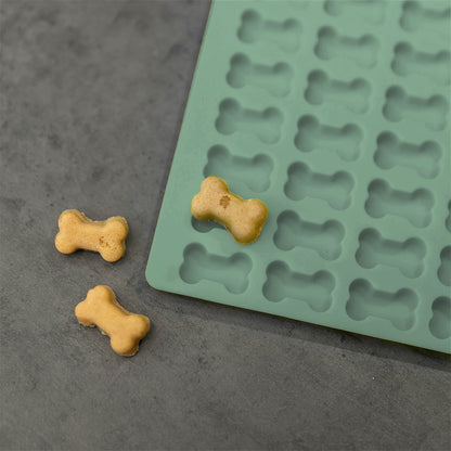 Nahaufnahme einer Trixie Backmatte 2cm Knochenform Grün. Auf und neben der Backmatte sind knochenförmige Kekse zu sehen.