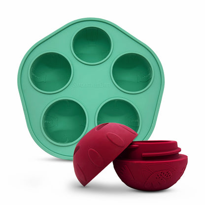 SmoothieDog Silikonform mit Schleckball, geöffnet: Eine grüne Silikonform mit fünf Mulden steht im Hintergrund, davor liegt der rote Schleckball – geöffnet in zwei Hälften, sodass das Innere sichtbar ist. Perfekt zum Befüllen mit gefrorenen Snacks für Hunde.